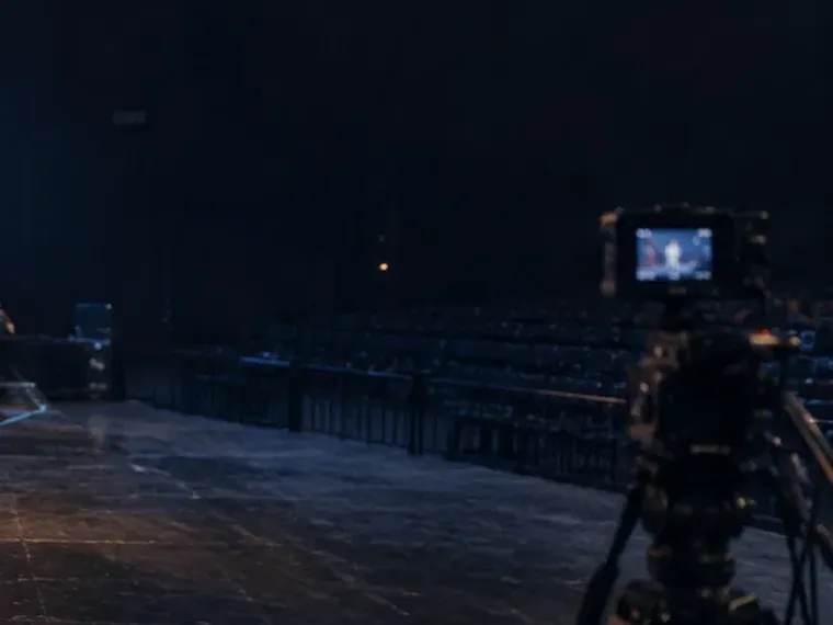 A camera on sticks facing an empty dark stage